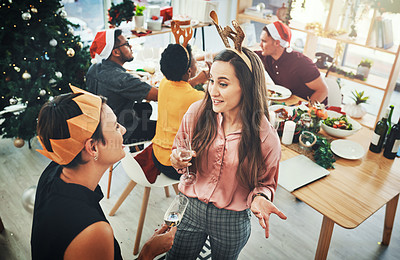 Buy stock photo High angle shot of two attractive female friends having a chat with their friends dining for Christmas in the background