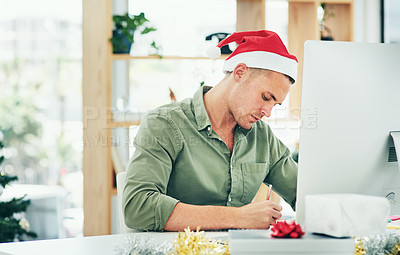 Buy stock photo Christmas, computer and businessman writing at a desk, thinking and planning in his office alone. Festive, season and employee working to meet deadline on xmas eve, write list, note or reminder 