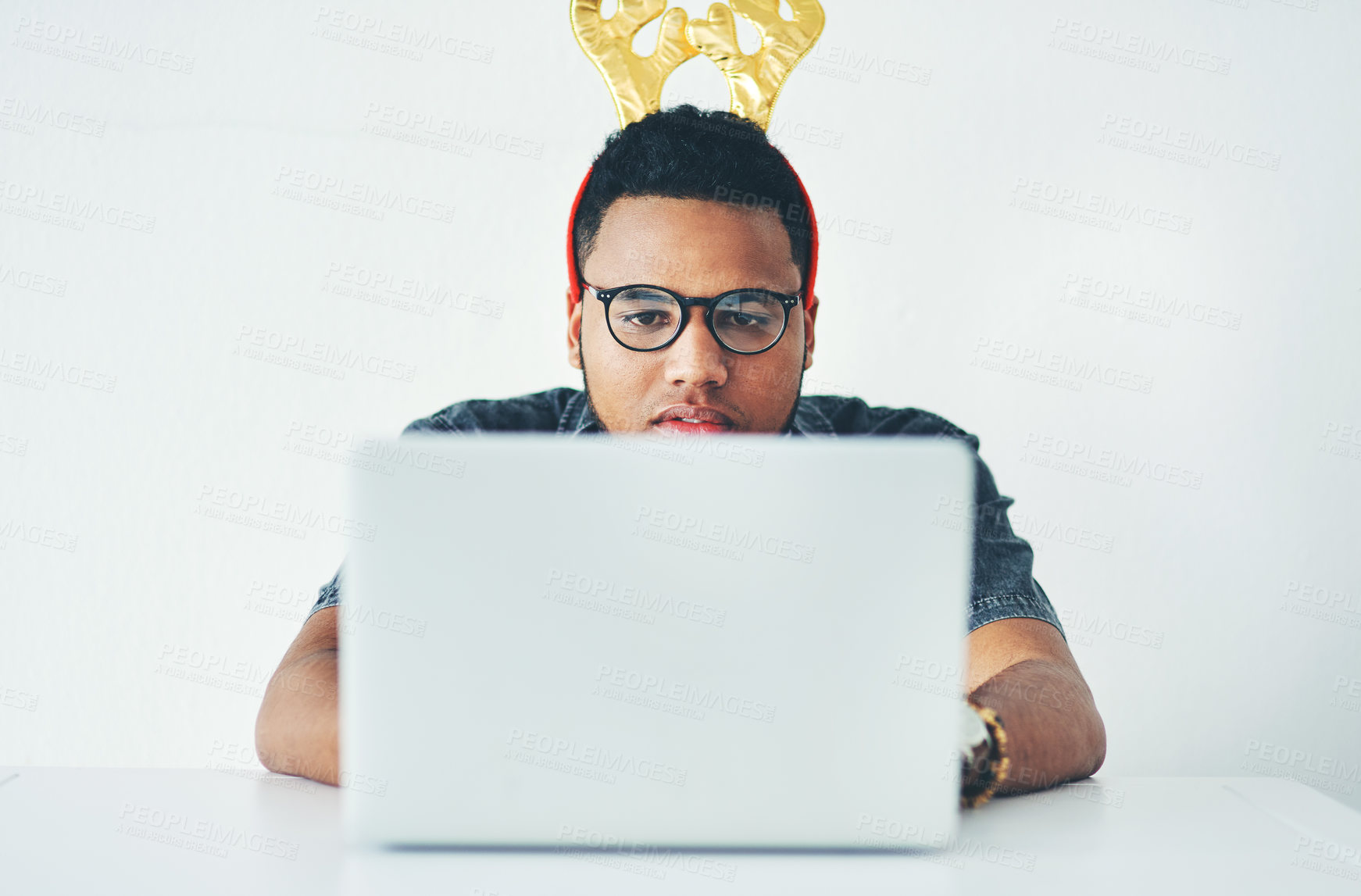 Buy stock photo Man, laptop and Christmas in office for reading, research and reindeer hat at media company. Person, computer and writer with review, feedback and thinking with xmas celebration at creative agency