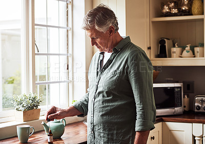 Buy stock photo Cropped shot of a relaxed senior man preparing a cup of tea with CBD oil inside of it at home during the day