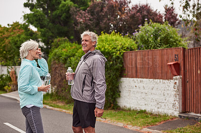 Buy stock photo Cropped shot of a cheerful senior couple drinking water after having a jog together outside in a suburb