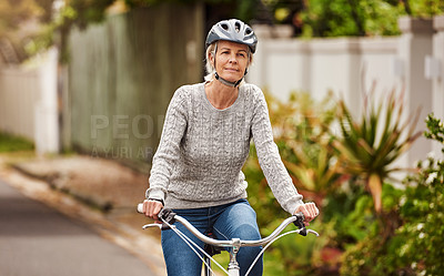 Buy stock photo Portrait of a cheerful senior woman riding on a bicycle by herself outside in a suburb