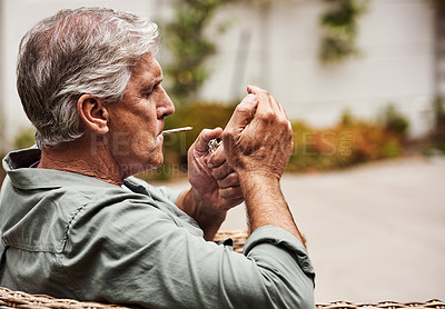 Buy stock photo Cropped shot of a relaxed senior man smoking a marijuana joint on his own inside of his garden at home during the day