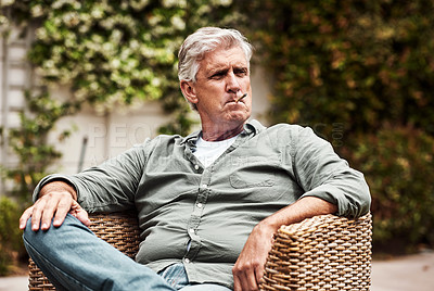 Buy stock photo Cropped shot of a relaxed senior man smoking a marijuana joint on his own inside of his garden at home during the day