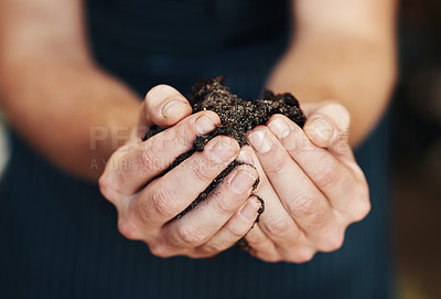Buy stock photo Cropped shot of an unrecognizable florist holding potting soil inside her plant nursery