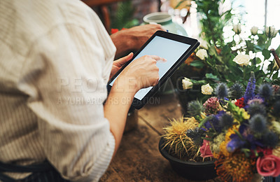 Buy stock photo Cropped shot of an unrecognizable florist using a digital tablet while working inside her plant nursery