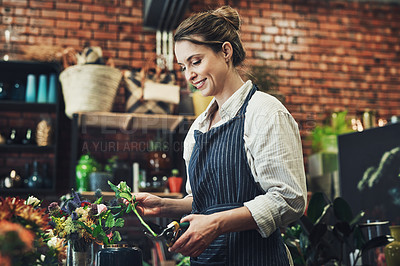Buy stock photo Cropped shot of an attractive young florist trimming and arranging flowers inside her plant nursery
