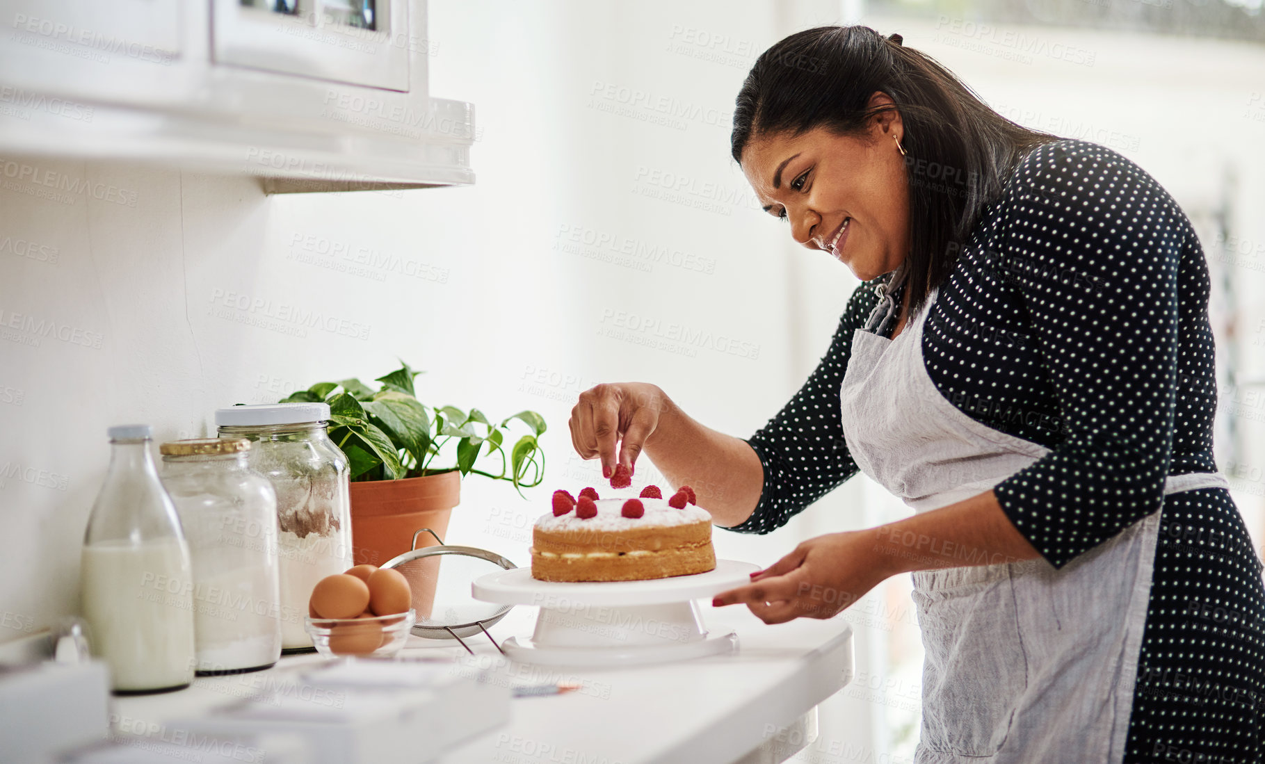 Buy stock photo Cropped shot of a woman decorating a cake in her kitchen