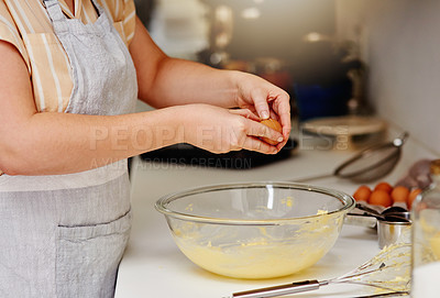 Buy stock photo Cropped shot of an unrecognizable woman adding eggs to her cake mixture