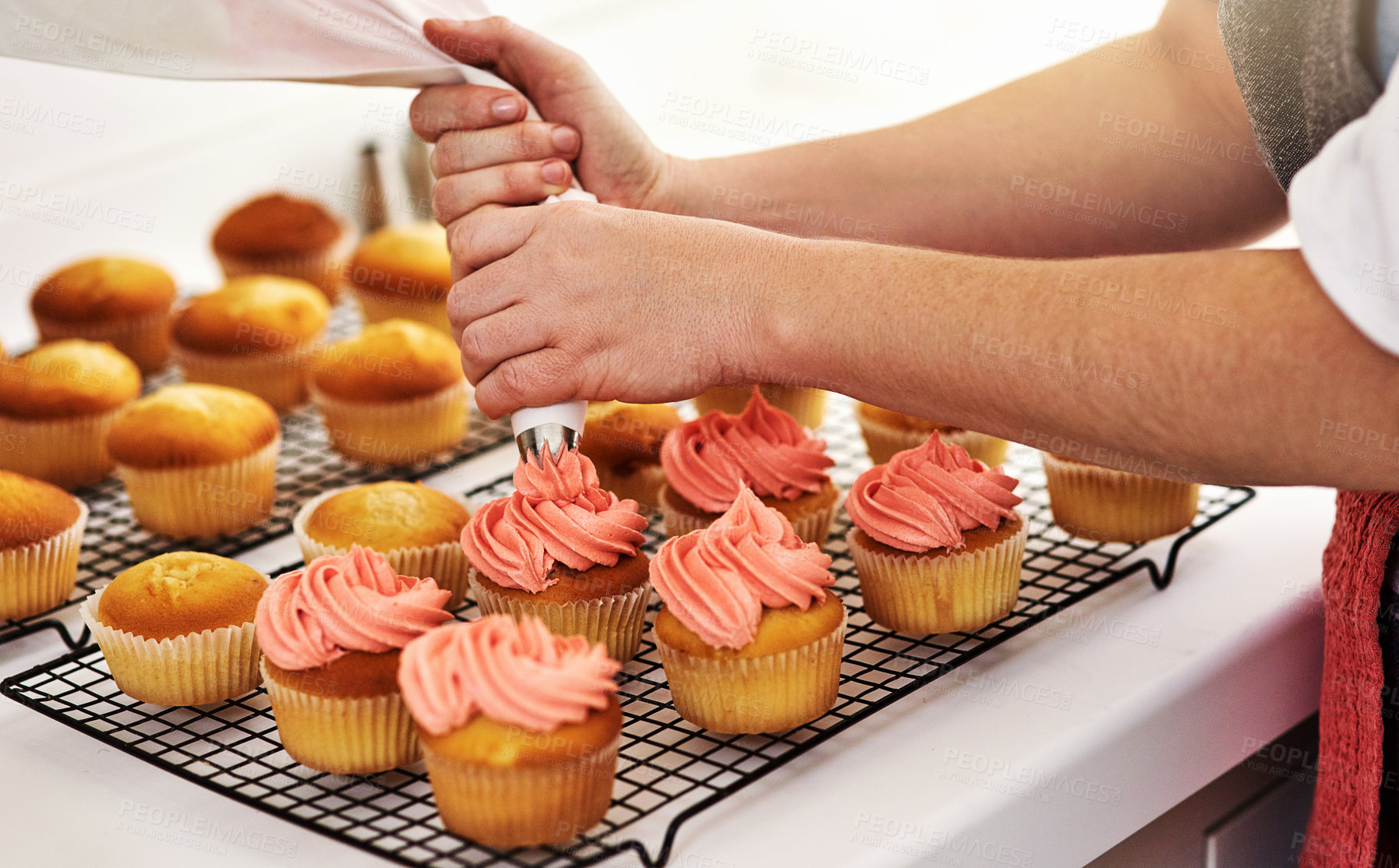 Buy stock photo Cropped shot of an unrecognizable woman piping icing onto her cupcakes
