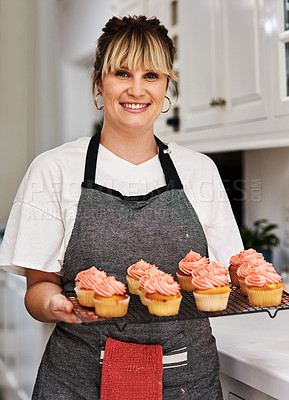 Buy stock photo Cropped shot of a woman holding freshly baked cupcakes in her kitchen at home