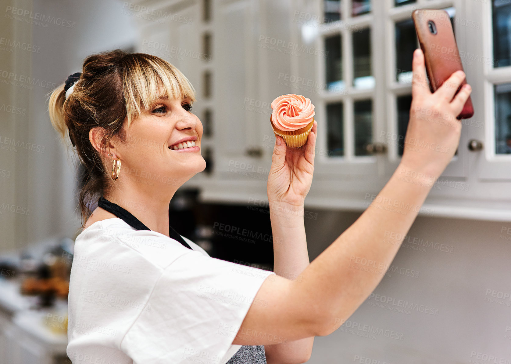 Buy stock photo Baker, happy woman and selfie of muffin in kitchen for social media, show sweets and online blog post in home. Pastry, cupcake and photography of dessert chef and food influencer cooking in house