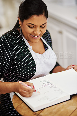 Buy stock photo Cropped shot of a making notes while wearing a apron