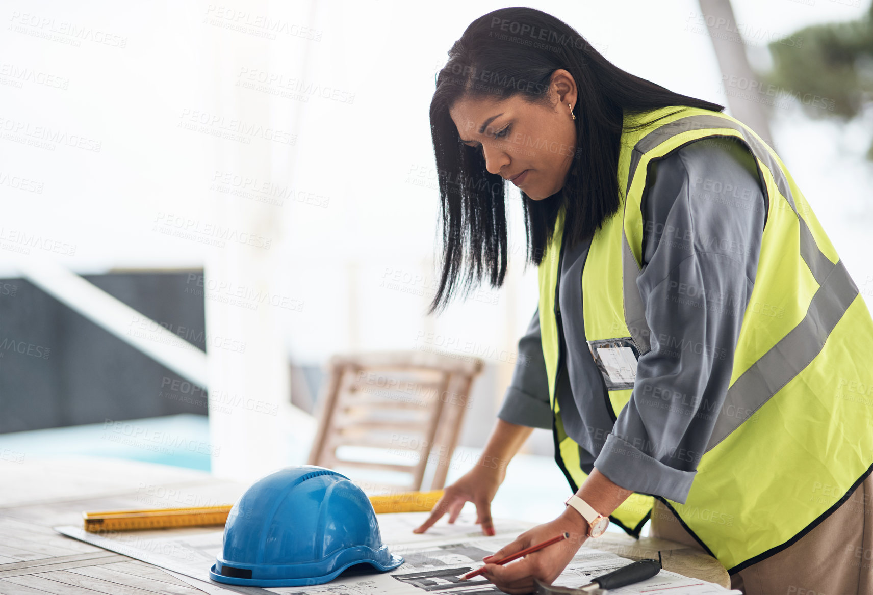 Buy stock photo Cropped shot of an attractive young female construction worker looking over plans on site
