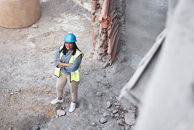 Buy stock photo High angle portrait of an attractive young female construction worker standing with her arms folded on site