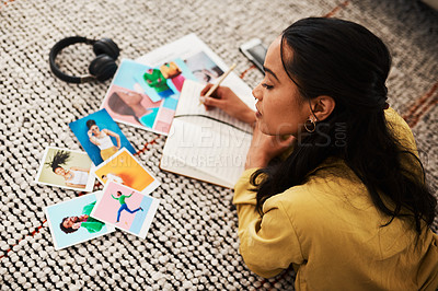 Buy stock photo Cropped shot of an attractive young businesswoman lying on her living room floor and sorting through polaroids for her blog