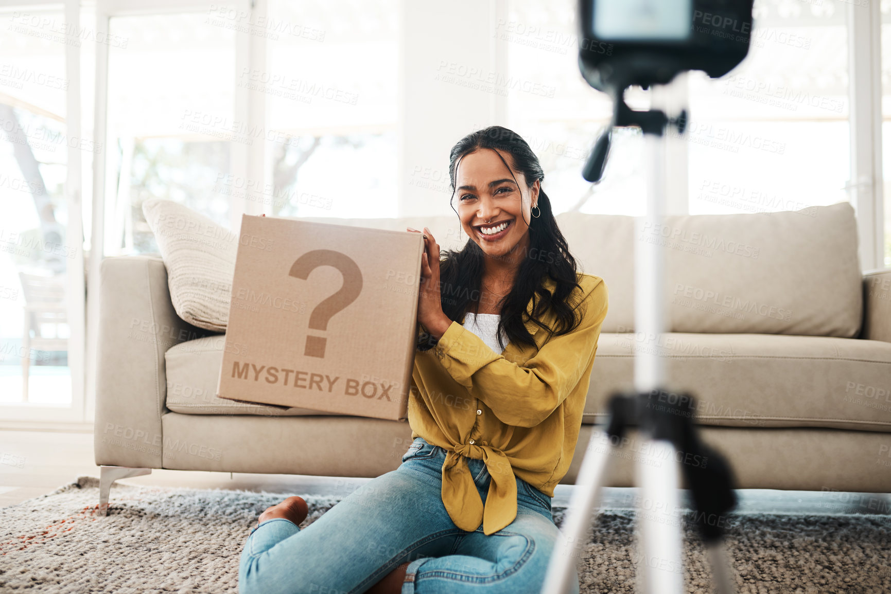 Buy stock photo Cropped shot of an attractive young businesswoman sitting in her living room and holding up a mystery box while vlogging