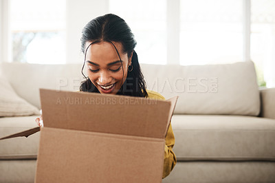 Buy stock photo Cropped shot of an attractive young businesswoman sitting alone on her living room floor and opening up a mystery box