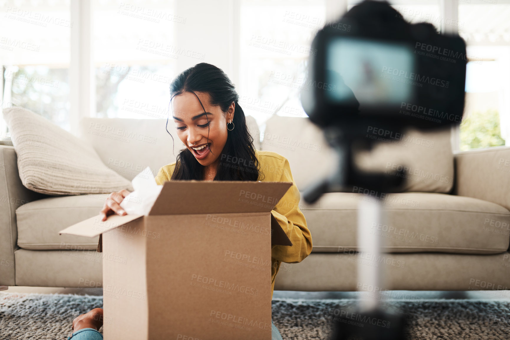 Buy stock photo Cropped shot of an attractive young businesswoman sitting in her living room and vlogging her reaction to a mystery box