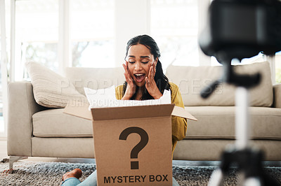 Buy stock photo Cropped shot of an attractive young businesswoman sitting in her living room and vlogging her reaction to a mystery box