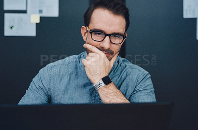 Buy stock photo Cropped shot of a handsome young male architect looking thoughtful while working on a laptop in his office