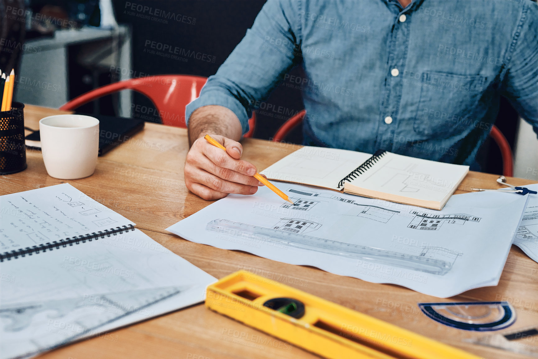 Buy stock photo Cropped shot of an unrecognizable male architect working with blueprints in a modern office