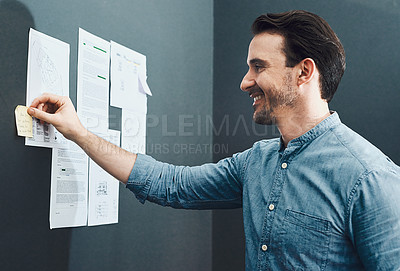 Buy stock photo Cropped shot of a handsome young man smiling while reading a sticky note in a modern office