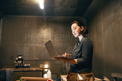 Buy stock photo Cropped shot of an attractive young female carpenter working on her laptop in the workshop