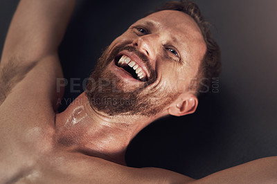 Buy stock photo Shot of a handsome young man smiling and feeling cheerful after working out indoors