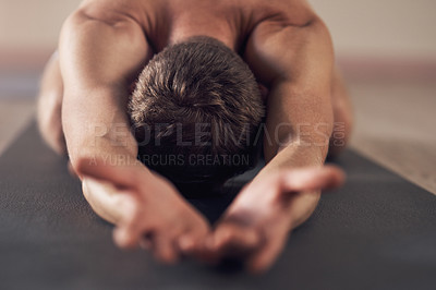 Buy stock photo Shot of an unrecognizable man stretching and practicing yoga indoors