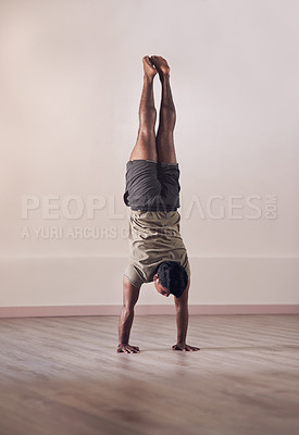 Buy stock photo Full length shot of an athletic young man doing a hand stand in studio