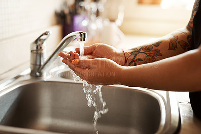 Buy stock photo Cropped shot of a woman washing her hands at the kitchen sink