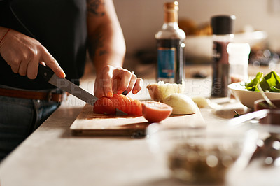 Buy stock photo Cropped shot of a woman slicing a tomato while preparing a meal at home
