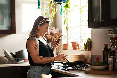 Buy stock photo Happy, woman cooking food with smartphone and in kitchen of a home. Dinner or lunch, multitasking and plus size, natural person with tattoo on cellphone following recipe motivation for healthy diet 