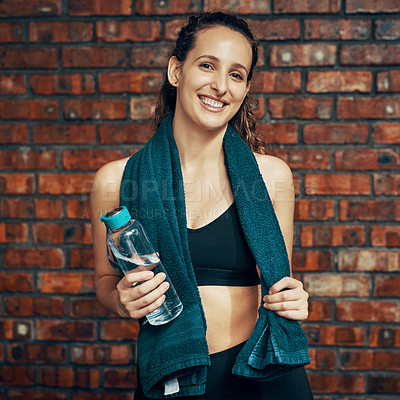 Buy stock photo Cropped shot of a young woman posing with a water bottle and her towel at the gym