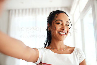 Buy stock photo Cropped portrait of an attractive young blogger standing alone in her home and taking a selfie