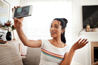 Buy stock photo Cropped shot of an attractive young blogger sitting in her living room and using her cellphone to record a vlog