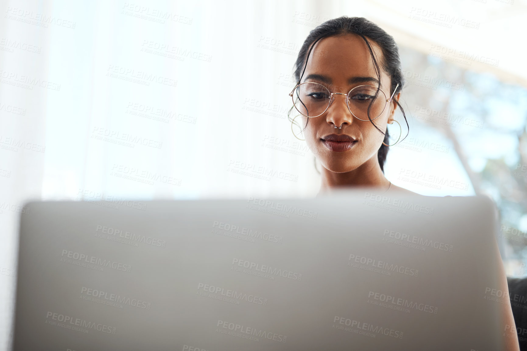 Buy stock photo Cropped shot of an attractive young businesswoman sitting in her home office and using her laptop