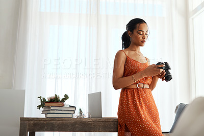 Buy stock photo Cropped shot of an attractive young businesswoman standing in her office and going through her blog images on her camera