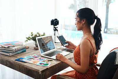 Buy stock photo Cropped shot of an attractive young businesswoman sitting and using her cellphone while blogging from her laptop