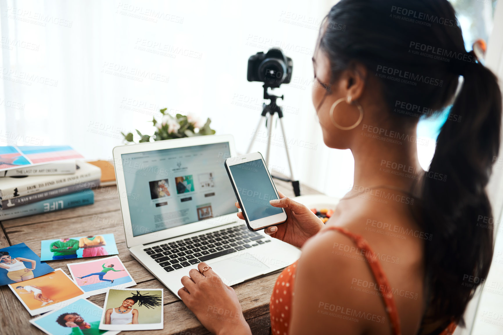 Buy stock photo Cropped shot of an unrecognizable businesswoman sitting and using her cellphone while blogging from her laptop