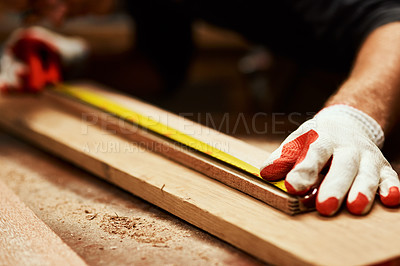 Buy stock photo Closeup of an unrecognizable male carpenter doing measurements on a piece of wood inside of a workshop at night