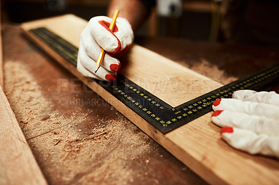 Buy stock photo Closeup of an unrecognizable male carpenter doing measurements on a piece of wood inside of a workshop at night