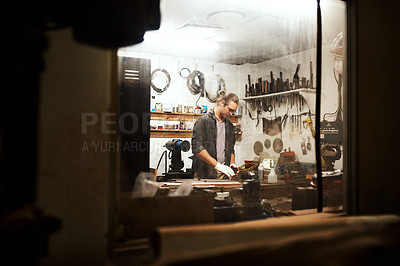 Buy stock photo Cropped shot of a focused young male carpenter working hard in his workshop at home during the night
