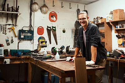 Buy stock photo Portrait of a cheerful young male carpenter taking a quick break while working inside of his workshop at home during the night