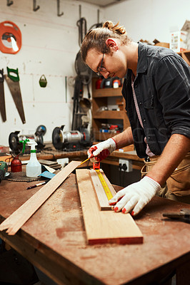 Buy stock photo Cropped shot of a focused young carpenter doing measurements on a piece of wood inside of a workshop at night