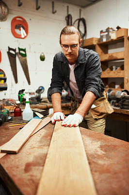 Buy stock photo Cropped shot of a focused young carpenter doing measurements on a piece of wood inside of a workshop at night