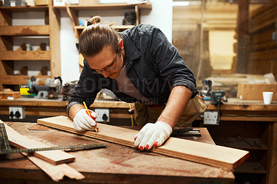 Buy stock photo Cropped shot of a focused young carpenter doing measurements on a piece of wood inside of a workshop at night
