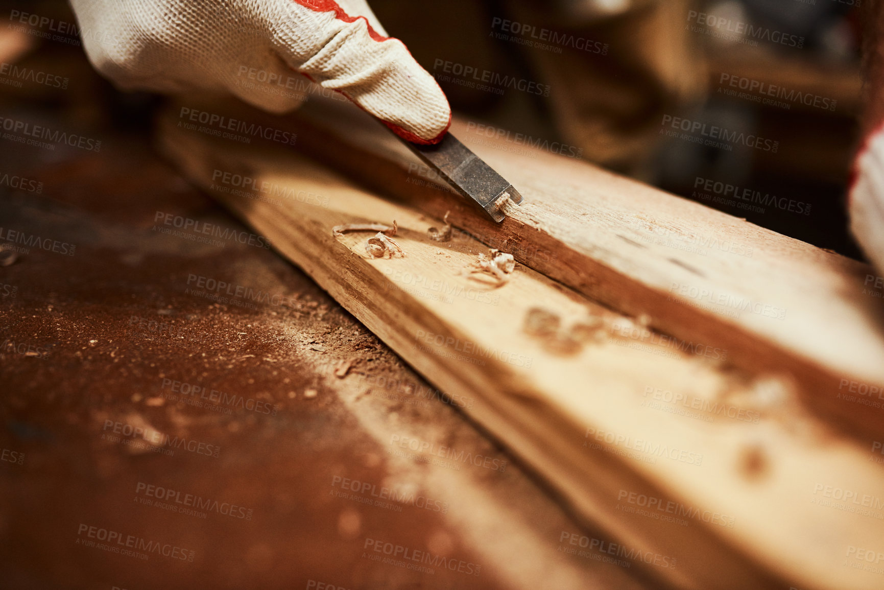 Buy stock photo Closeup of an unrecognizable carpenter filing down a piece of wood inside of a workshop at night