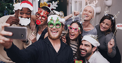 Buy stock photo Christmas, party and friends taking a selfie on a phone together with goofy, funny and silly props. Diversity, festive and happy people taking picture on a smartphone at festive xmas event at a home.